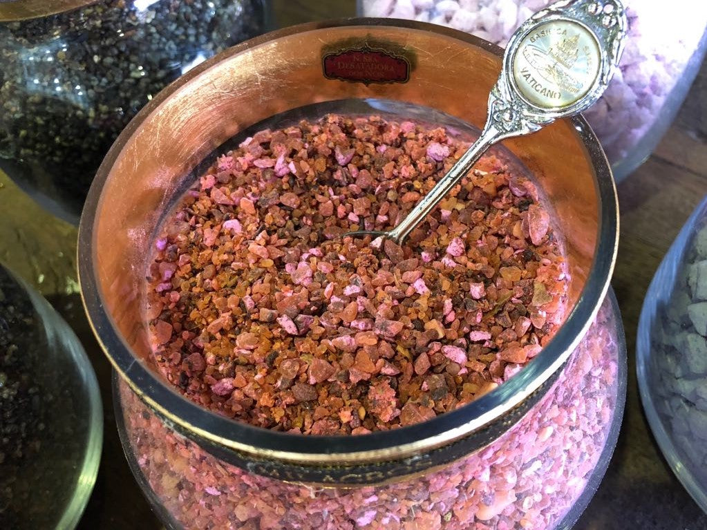 Milagros Our Lady Untier of Knots resin incense in a copper burner bowl with a Vatican-themed dosing spoon.