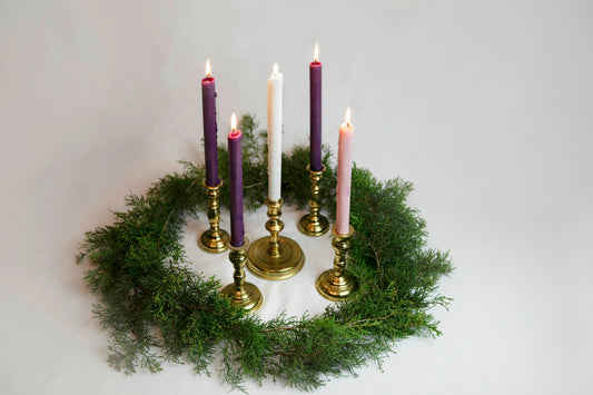 Advent wreath with three purple candles, one rose candle and a white Christ candle in brass holders